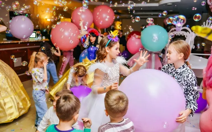 A big children's party with balloons, bubbles and characters